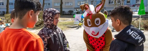 Mensch im Osterhasenkostüm spricht mit Kindern