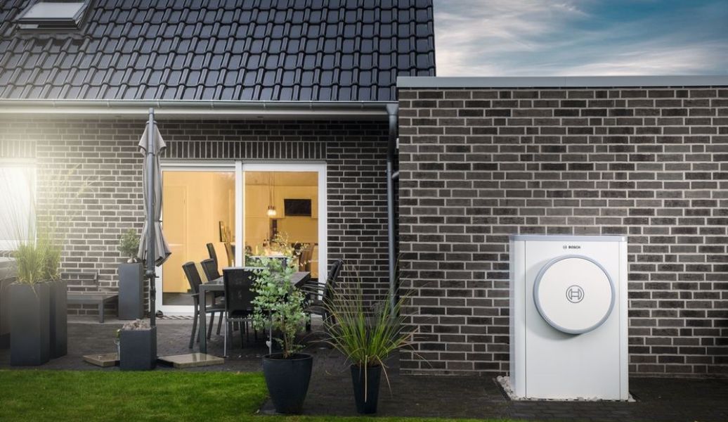 Haus mit Wärmepumpe von Bosch in weiß mit Gartenelementen davor