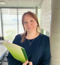 Frau lehnt am Pfeiler mit Mappe in der Hand