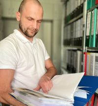 Mann steht am Aktenschrank und liest
