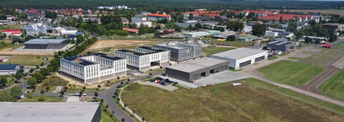 Vogelperspektive auf Gewerbeflächen mit Bebauung und Grünfläche bei Sonne