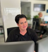 Frau sitzt am Tisch und lächelt