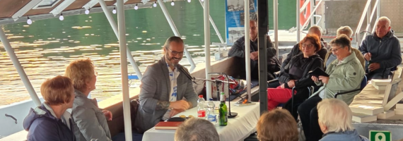 Menschen sitzen auf Fähre und schauen zu Autor in der Mitte