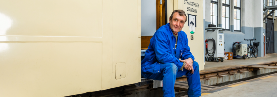 Mann in Blaumann sitzt an alter Bahn