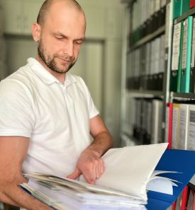 Mann steht am Aktenschrank und liest