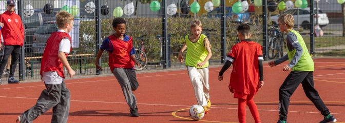 Kinder auf rotem Sportplatz spielen Fußball