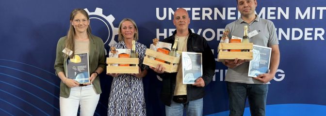 2 Frauen und 2 Männer mit Auszeichnung vor blauer Wand