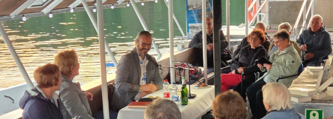 Menschen sitzen auf Fähre und schauen zu Autor in der Mitte