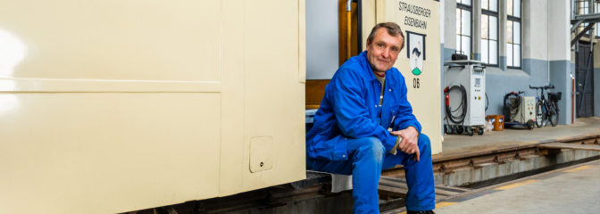 Mann in Blaumann sitzt an alter Bahn